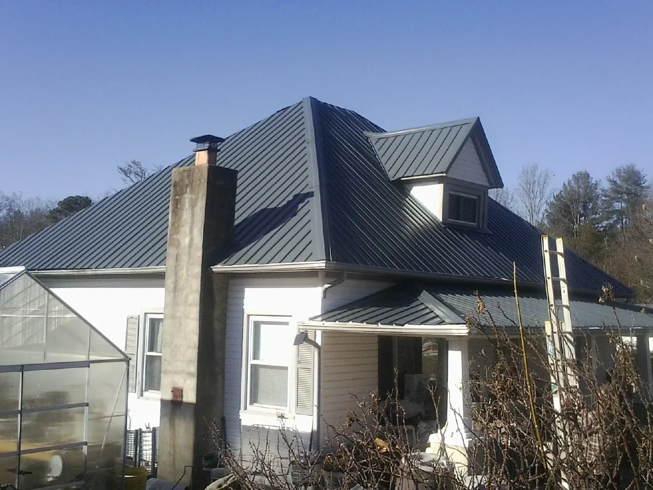Dark blue standing seam metal roof on a white farmhouse with dormer — Slate & Tile Roof Repair by Roofing Brothers in Three Rivers