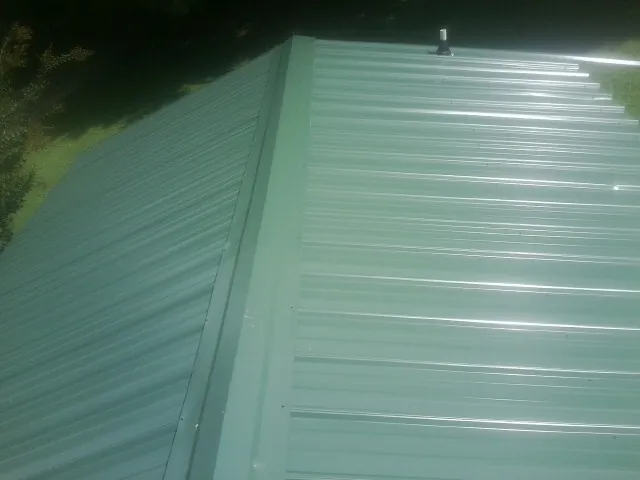New green metal panels meeting at the ridge of a roof — Flat Roof Repair work by our crew in Three Rivers