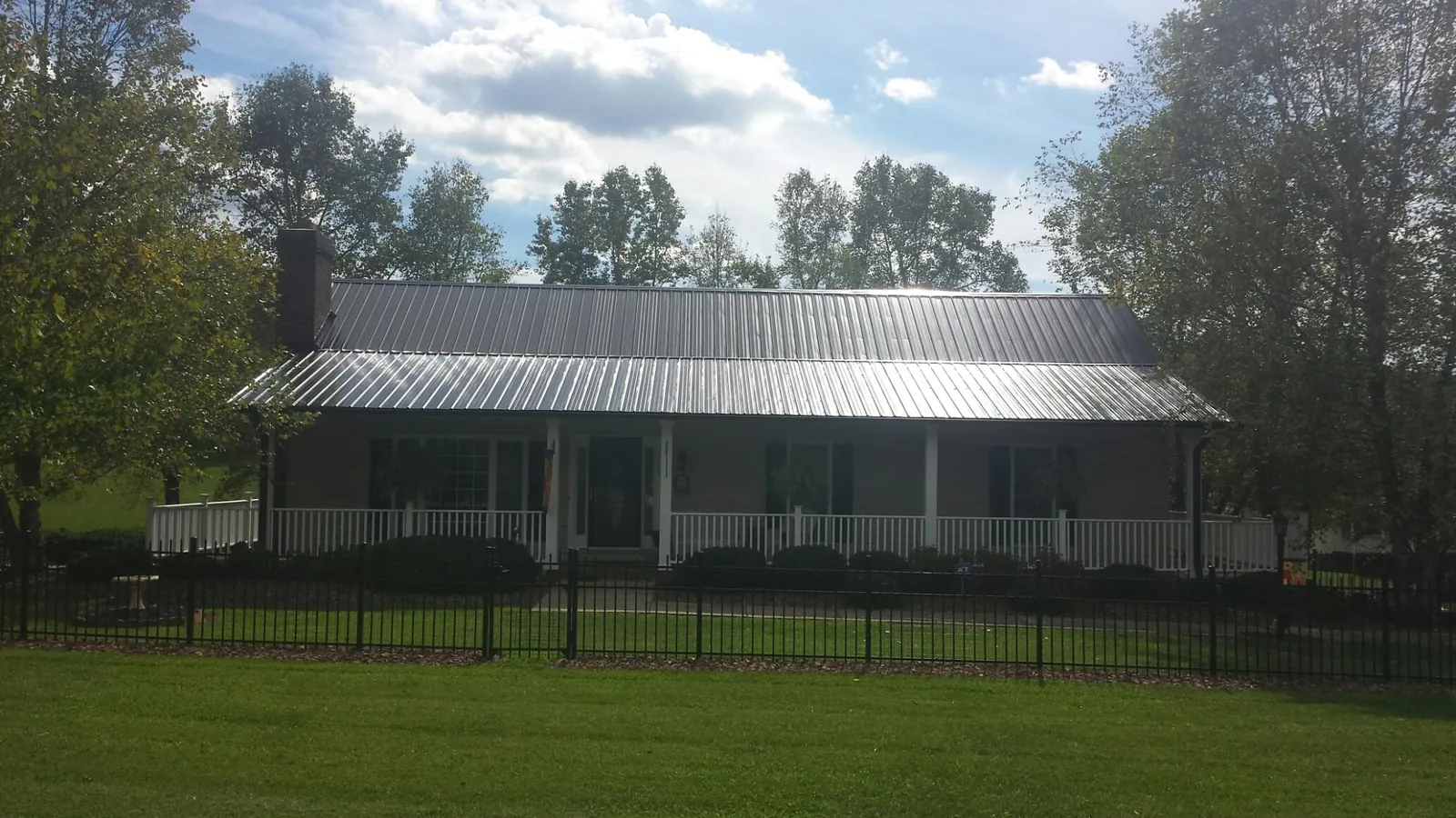 Gray metal roof on a brick ranch with a full width front porch — Gutter Guard Installation work by our crew in Three Rivers